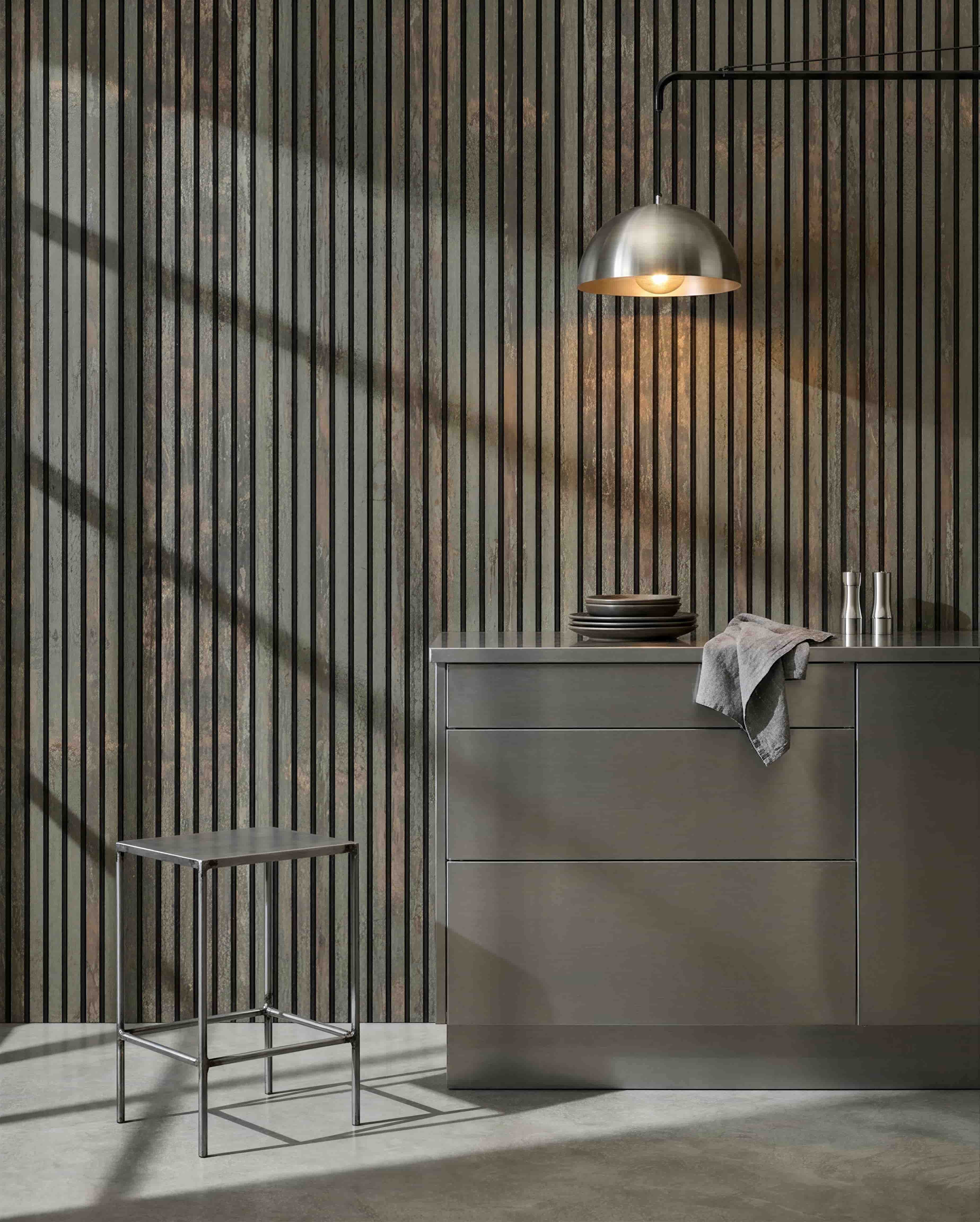 Minimalistische keuken met metalen kruk, grey kookeiland en servies, met een WoodUpp Akupanel akoestisch houten paneel in Oxide Grey/Black Felt voor geluidsbeheersing.
