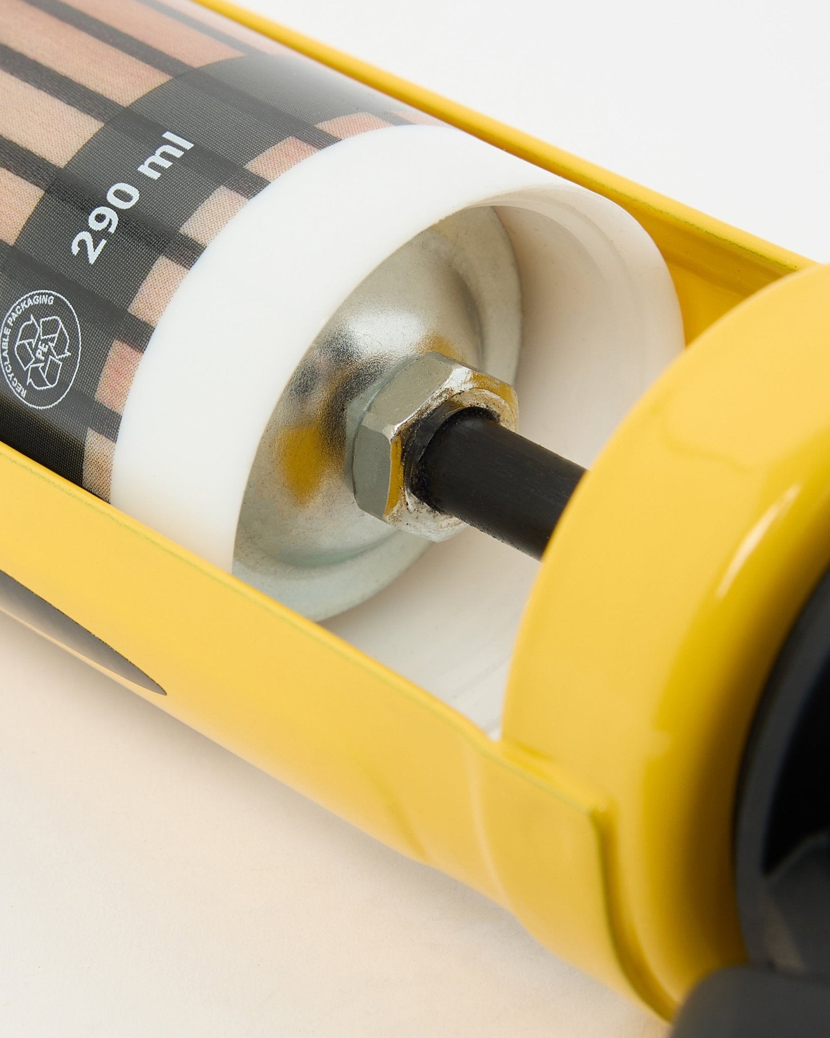 Gedetailleerde weergave van het WoodUpp voegkitpistool (290 ml), een gele installatietool met metalen onderdelen die wordt gebruikt voor het monteren van akoestische panelen en roomdividers.