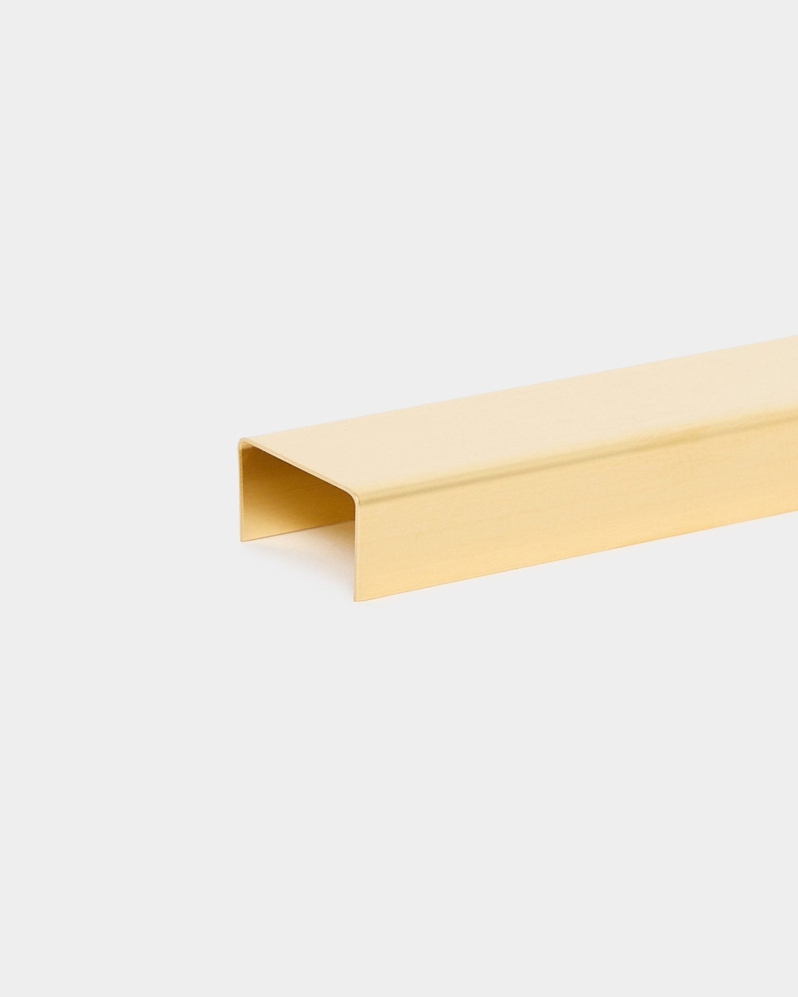 Le Liva | Cover en brass, 60 cm, de WoodUpp est un accessoire de finition métallique en forme de U pour les panneaux acoustiques Akupanel, présenté sur un fond uni gris clair.