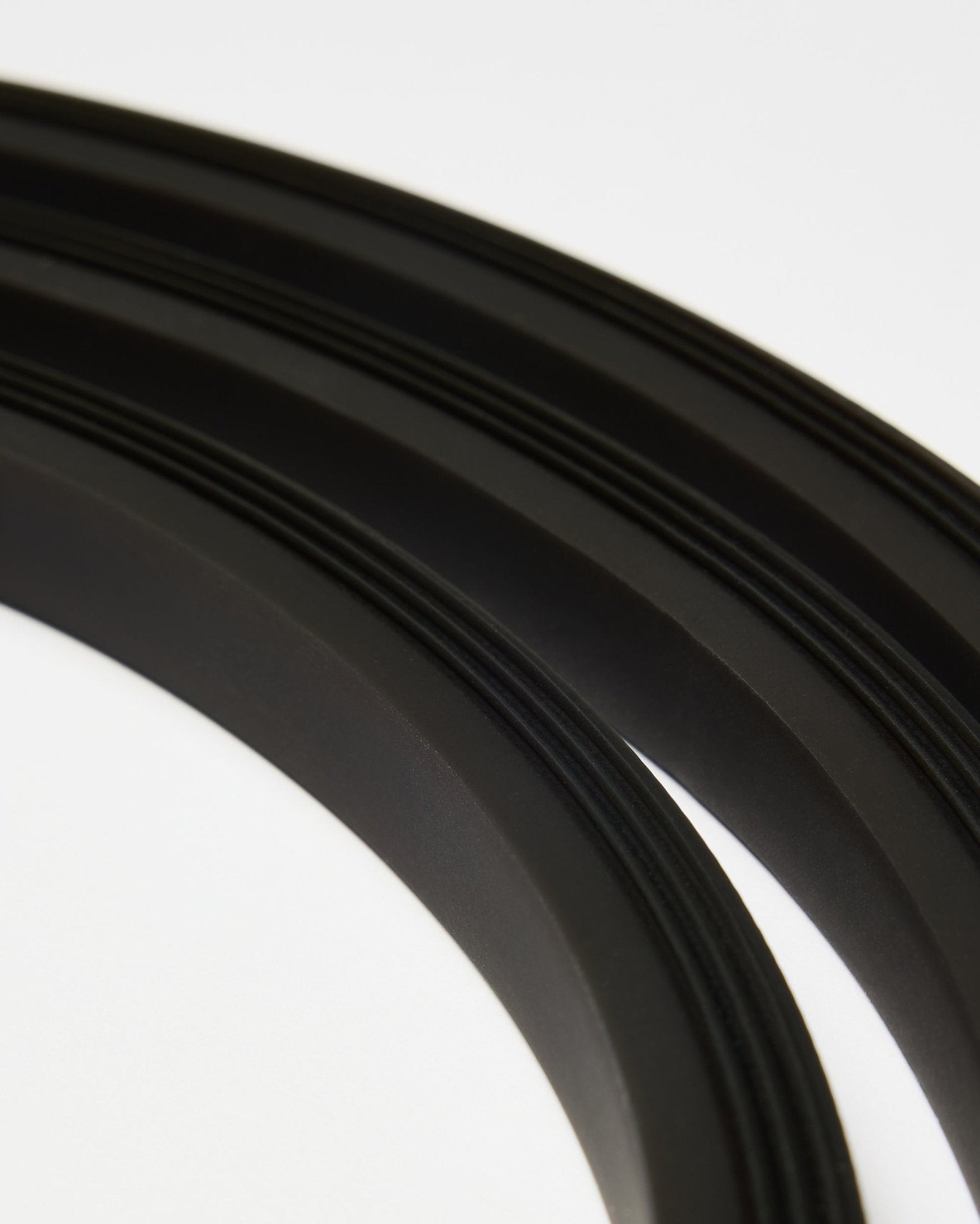 Gros plan sur la bande LED black Lumi de WoodUpp (300 cm), disposée en lignes courbes sur fond blanc, en accord avec le style minimaliste Akupanel Panneau acoustique.