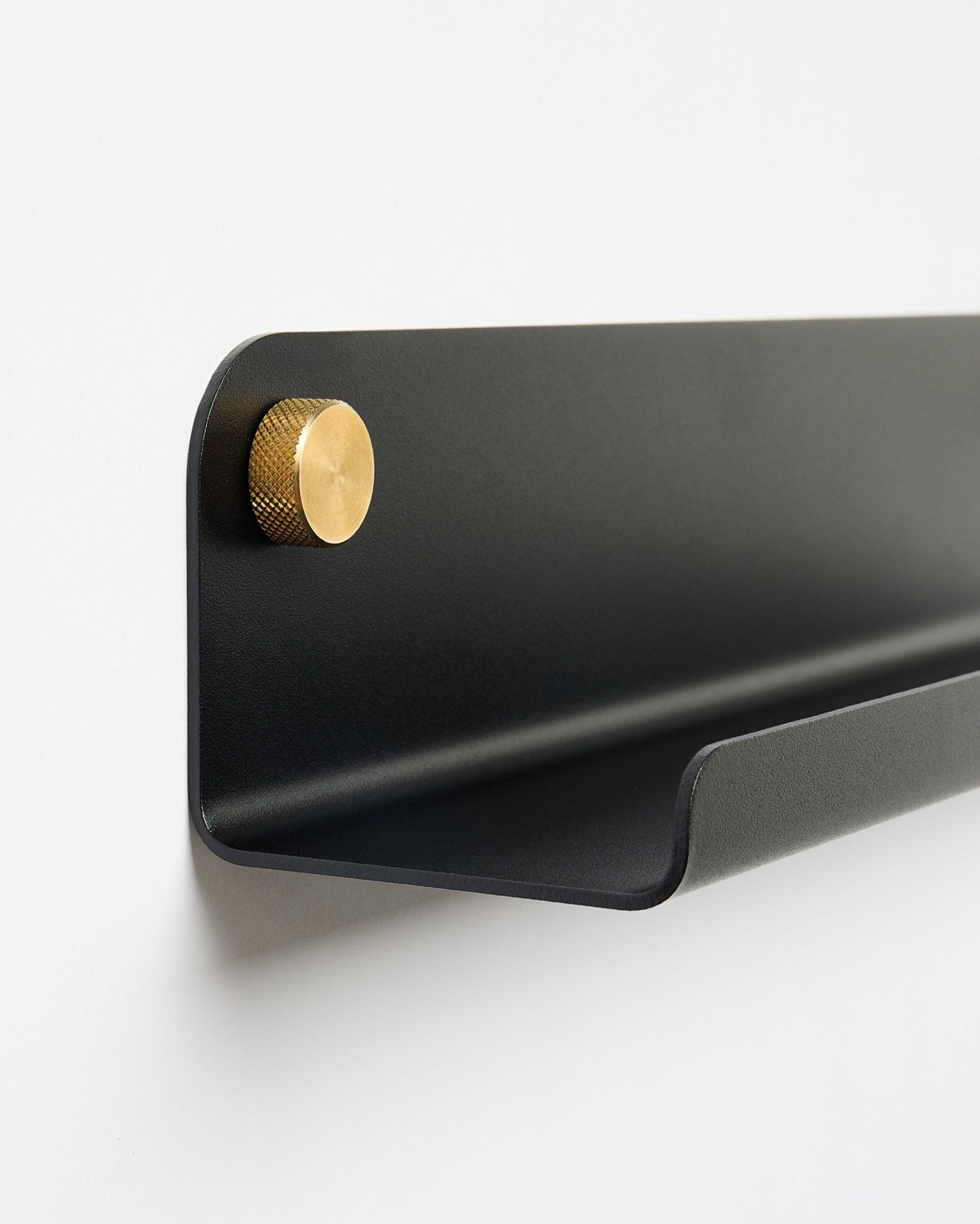 Le Norr | Étagère étroite en black (115,9 cm) avec un bouton doré à gauche, par WoodUpp, montée sur un mur blanc uni.