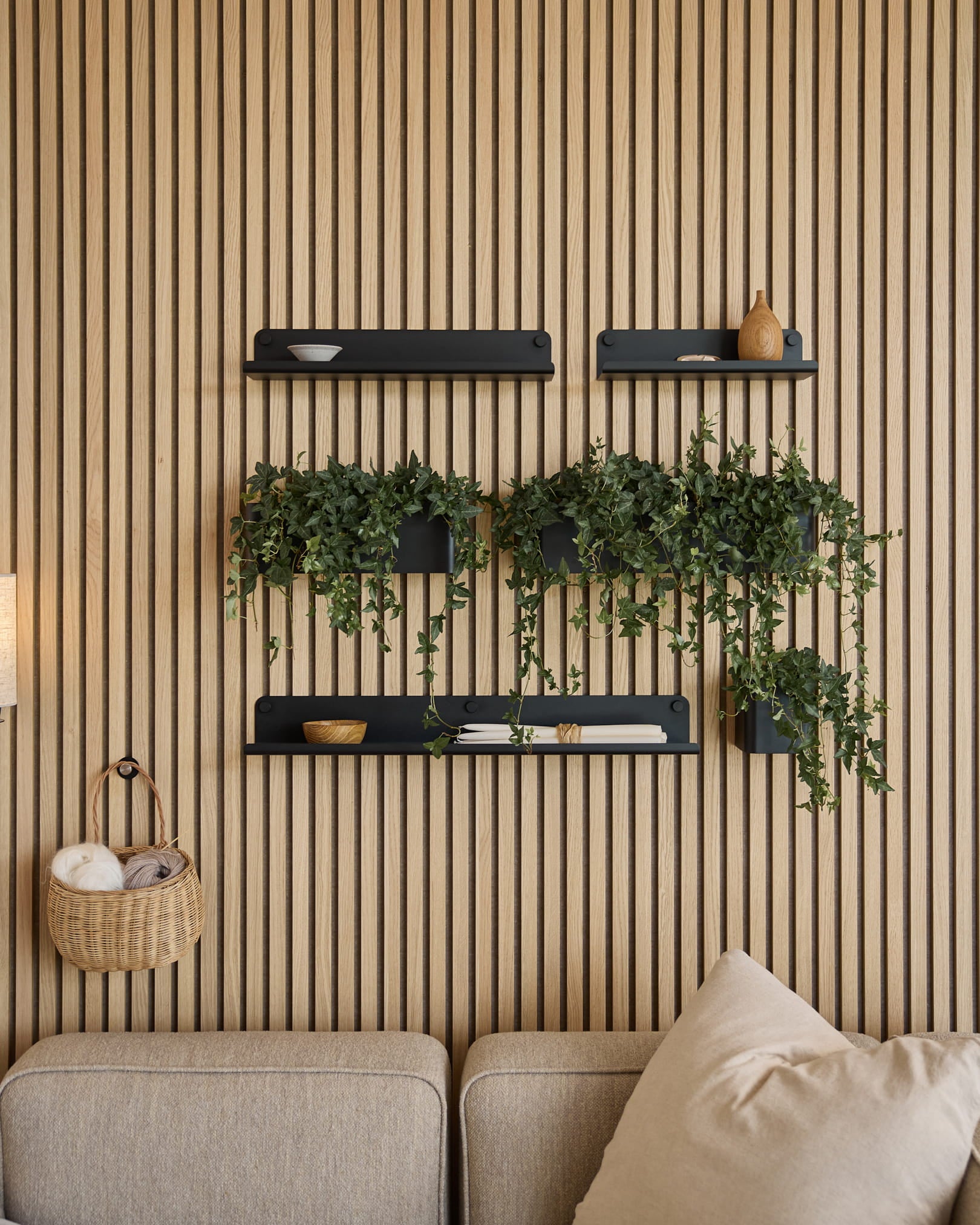 Moderne woonkamer met een Scandinavisch akoestisch lattenwandpaneel, black planken, hangplanten in WoodUpp’s Norr Plant Box (35,9 cm, Black), en een beige bank.