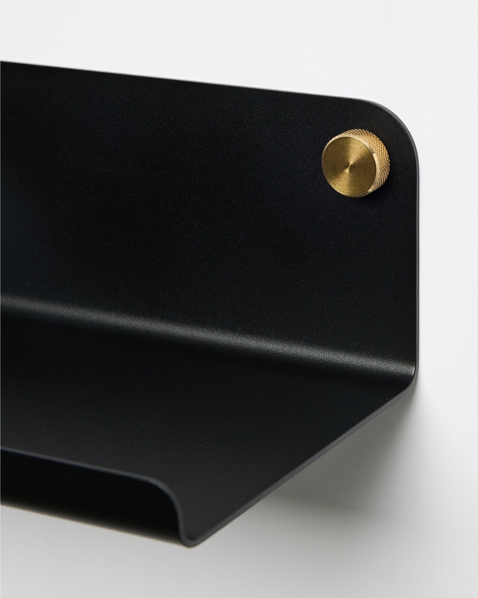 Close-up van de WoodUpp Norr Wide Shelf in black, 35,9 cm, met een gebogen rand, bevestigd aan de muur met een ronde brass schroef. Minimalistisch Scandinavisch design.