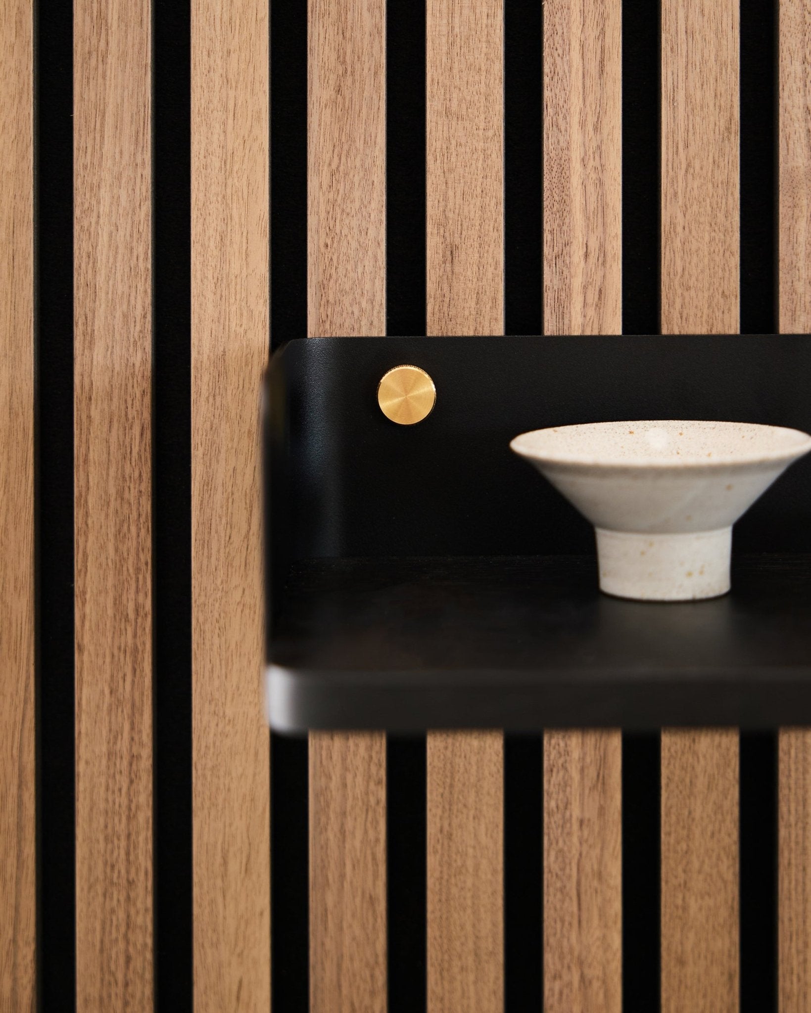 Keramische kom op de Linn Bookshelf van WoodUpp, 39,9 cm in black oak met vertical black latten en een accent in brass, als weerspiegeling van Scandinavisch minimalistisch design.