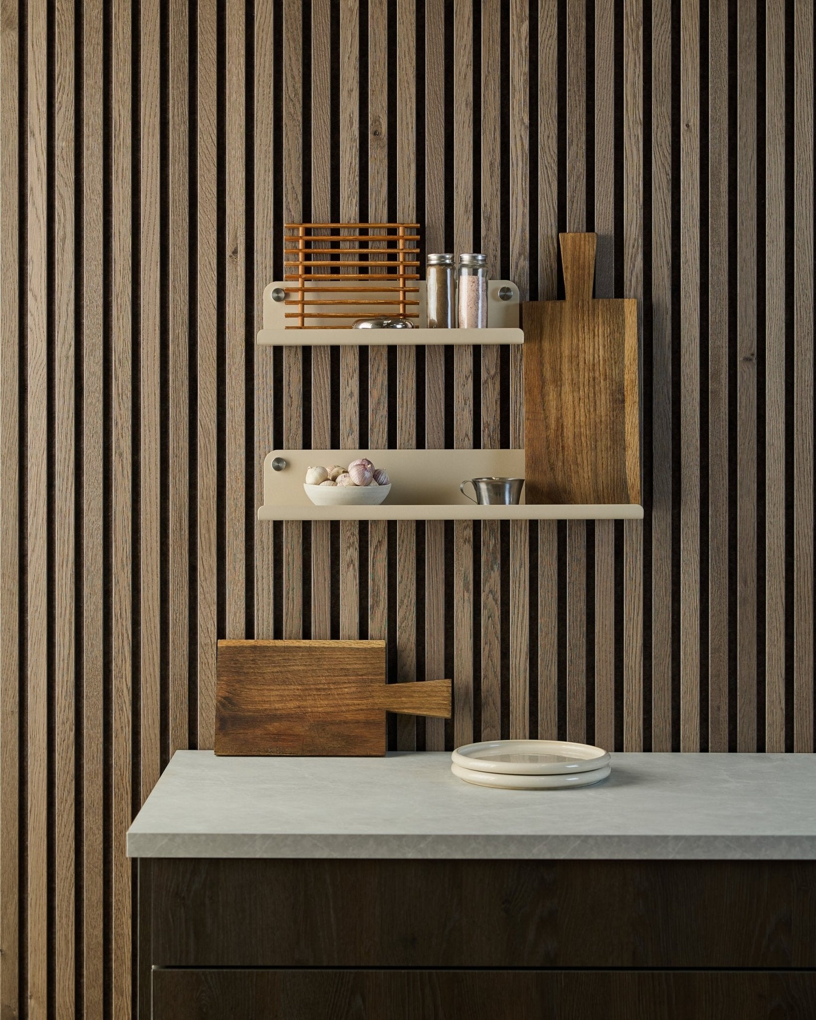 Minimalistische keuken met een Scandinavische houten akoestische lattenwand in Akupanel, open planken met kruiden en kommen, en een aanrecht met witte borden en een snijplank.