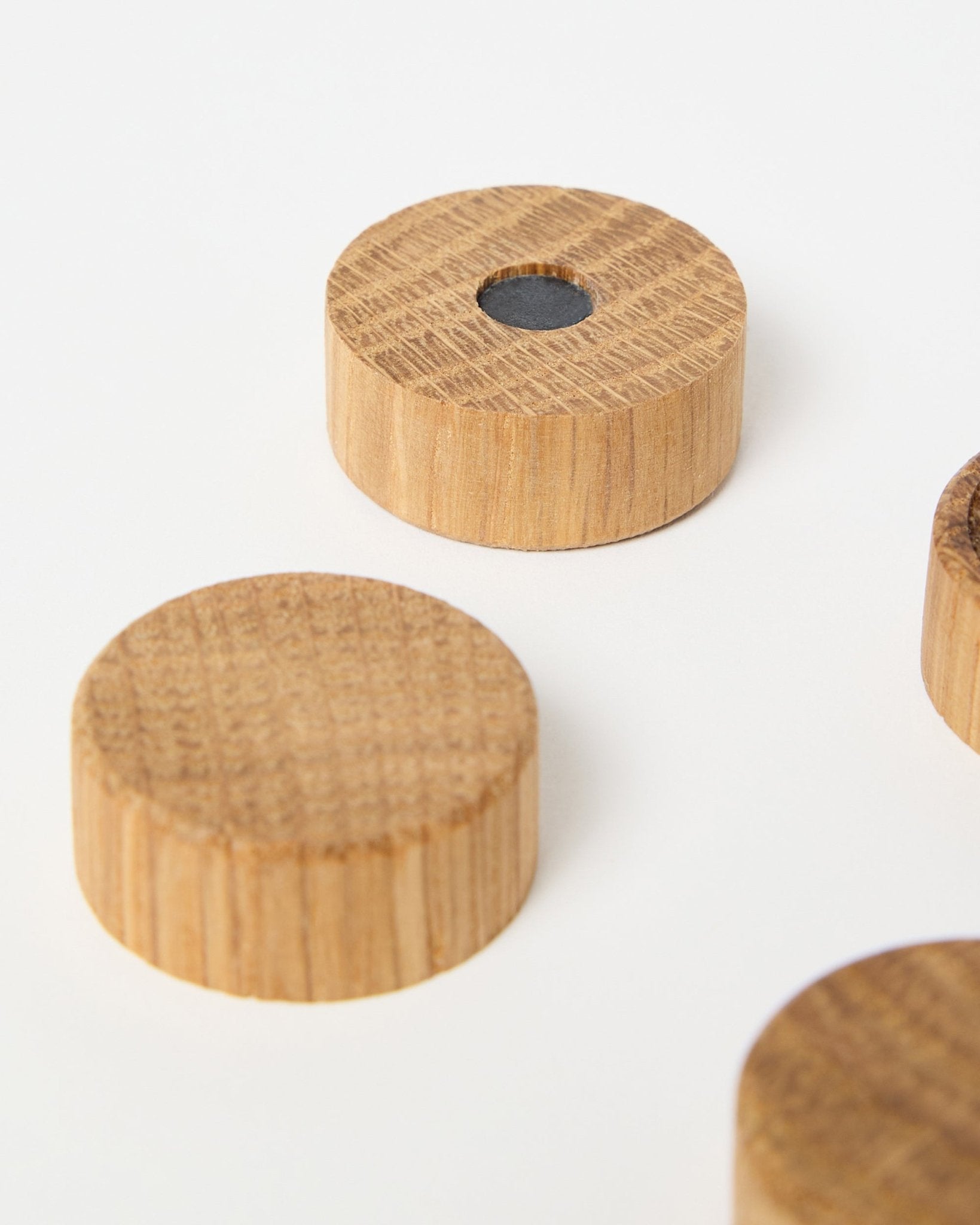 Set van vier natural oak magneten van WoodUpp, ontworpen voor gebruik met Akupanel akoestische houten panelen, waarvan één met een centrale neodymiummagneet voor extra grip, weergegeven op een witte achtergrond.