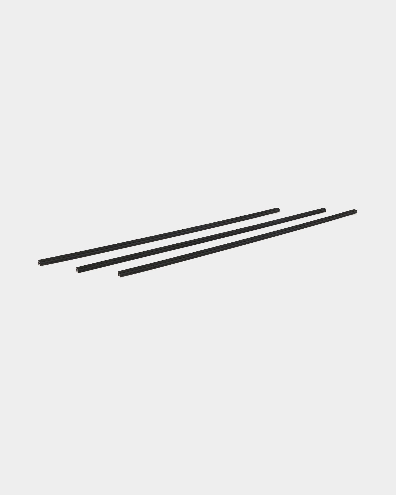 Drie black Dupps Pop-on Cable Covers (set van 3) van WoodUpp, ontworpen als accessoires voor Akupanel, diagonaal geplaatst op een effen witte achtergrond.