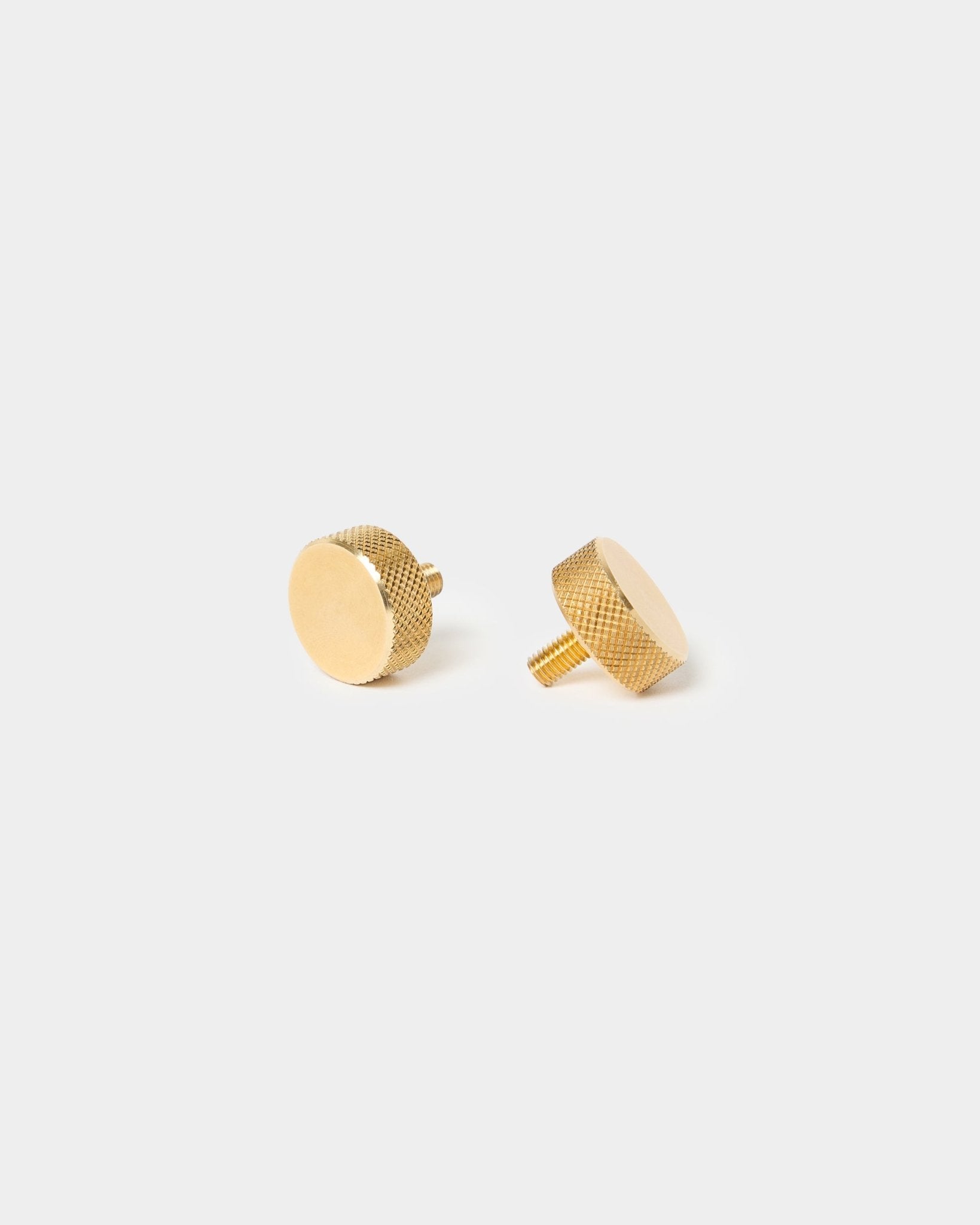 Paar WoodUpp brass vingerschroeven (M5x10 mm, 20x8.8), met gestructureerde randen en korte schroefstiften, ontworpen voor Akupanel accessoires, op een effen lichte achtergrond.