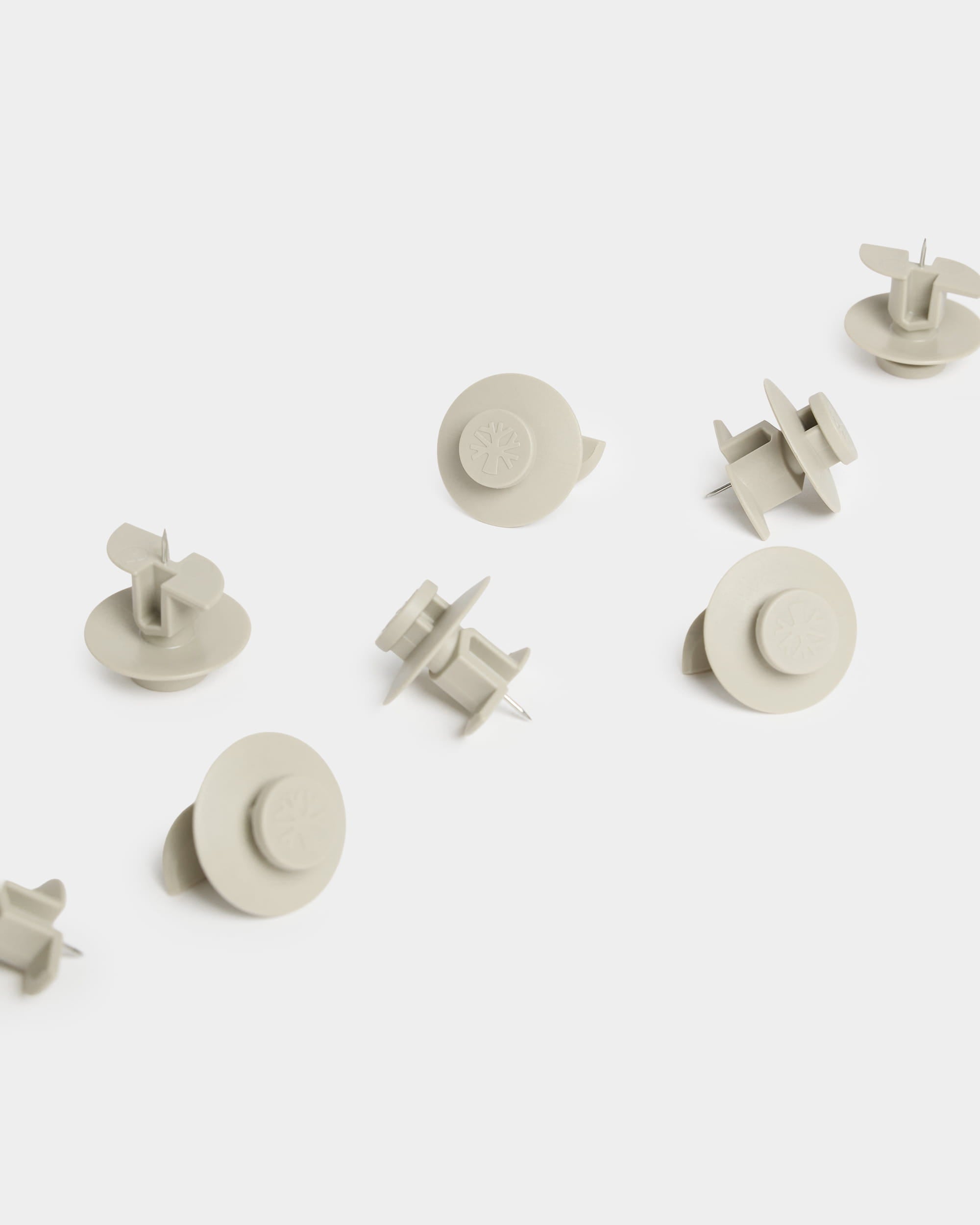 Tien beige WoodUpp Dupps-prikpinnen (Light) met ronde kopjes zijn op een wit oppervlak geplaatst; ze zijn bedoeld voor gebruik met accessoires voor akoestische panelen.