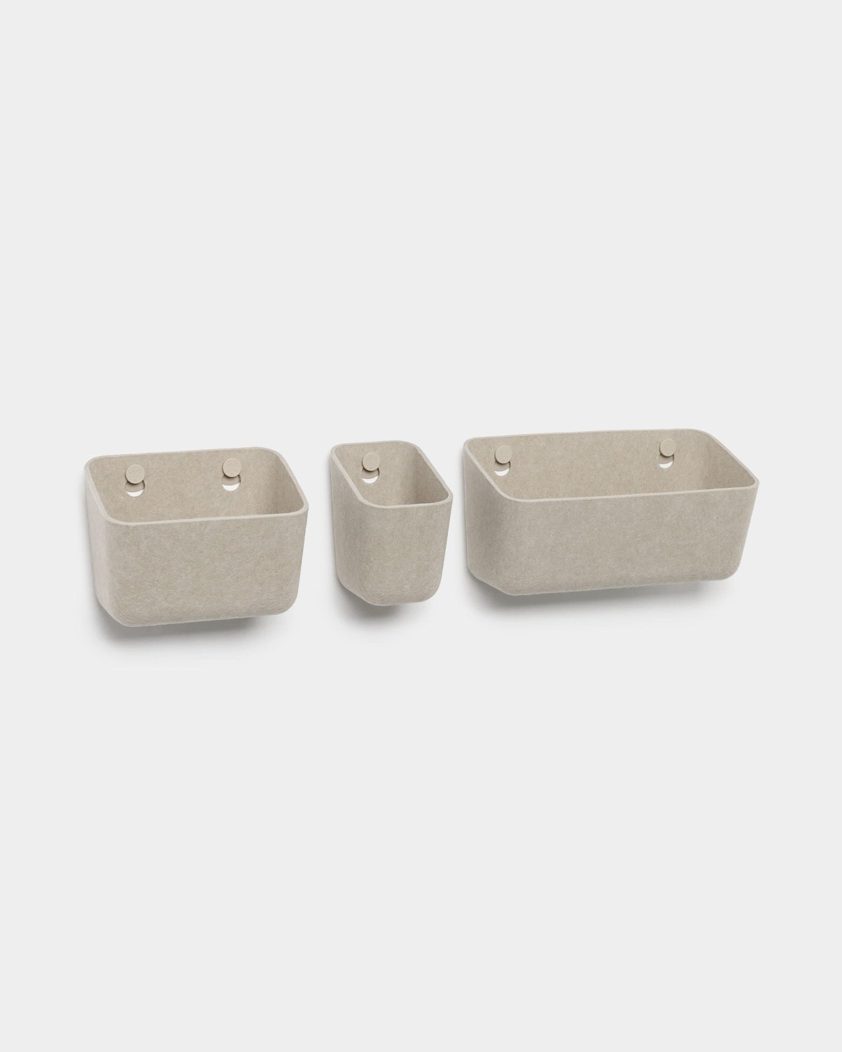 Lot de trois boîtes en feutre WoodUpp Luva de couleur beige, chacune dotée de deux trous ronds permettant de les suspendre, photographiées sur fond blanc.