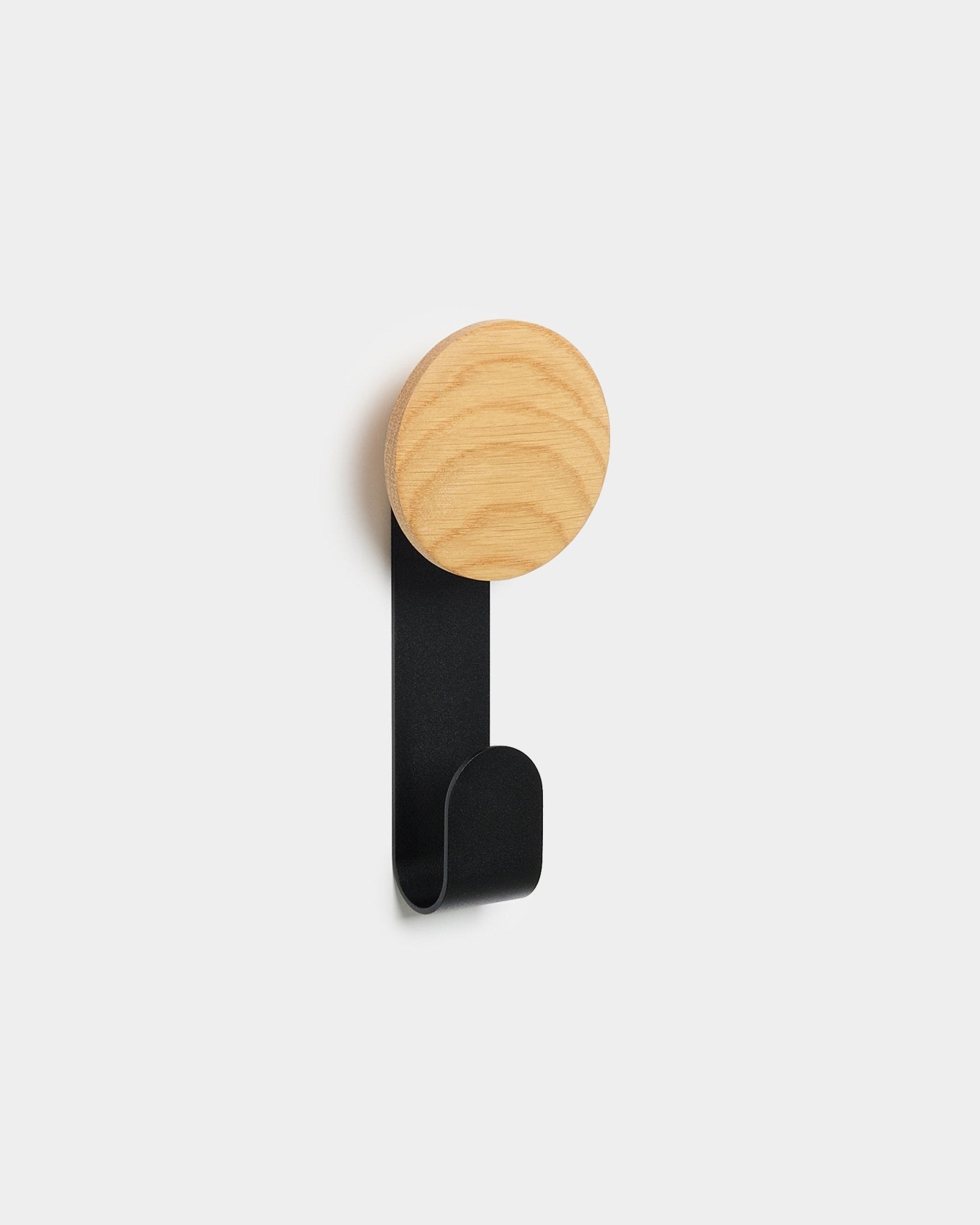 De Linn Vertical Hanger van WoodUpp met een ronde bovenkant van natural oak en een metalen haak van black, ontworpen om accessoires op Akupanel Nordic akoestische houten panelen te hangen.