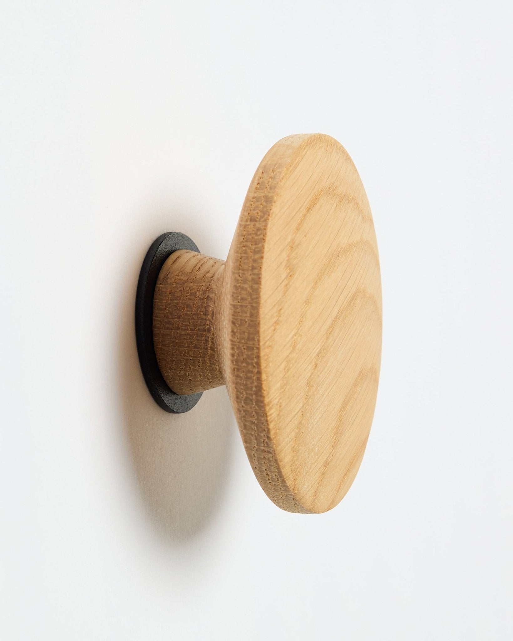 WoodUpp Linn I Single Hanger in natural oak, een ronde wandhaak met black basis, ontworpen als accessoire voor montage op Akupanel akoestische houten panelen.
