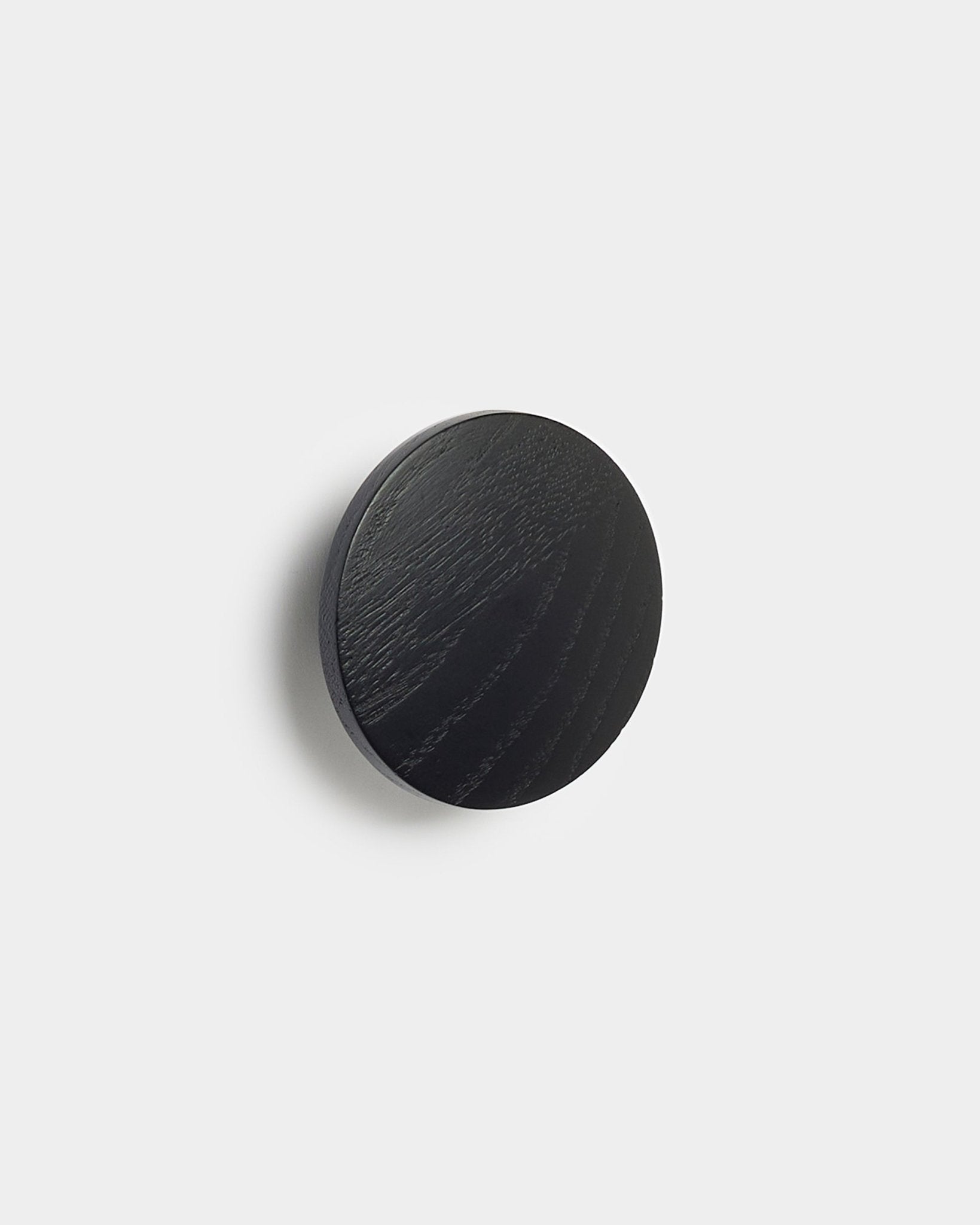 De Linn | Single Hanger in black oak van WoodUpp, een rond accessoire voor Akupanel akoestische panelen, getoond tegen een strakke witte achtergrond.