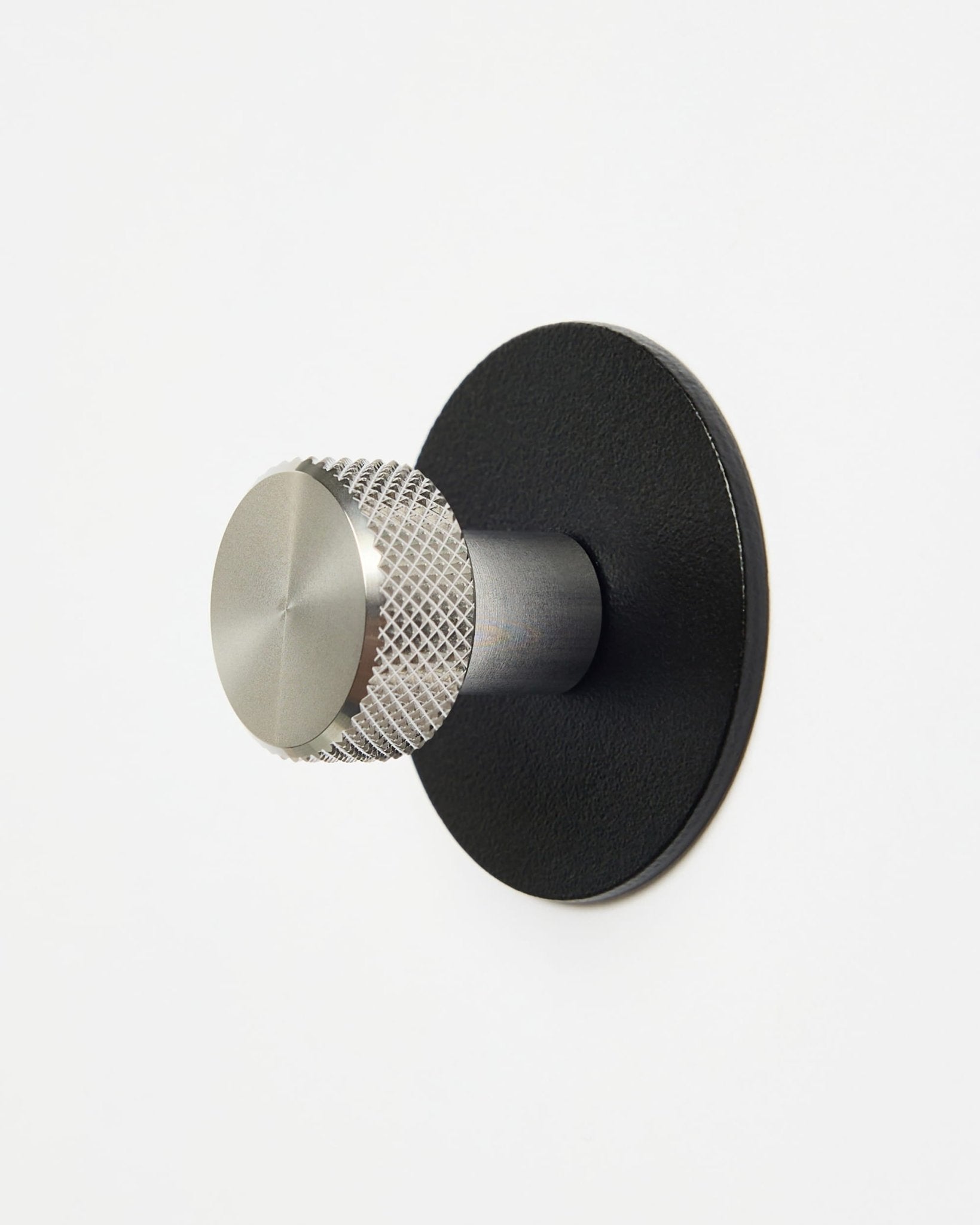 WoodUpp Norr | Coat Hook X1 in black en roestvrij steel, gemonteerd op een strakke witte muur, ontworpen als accessoire uit de CREATE-collectie voor Akupanel systemen.