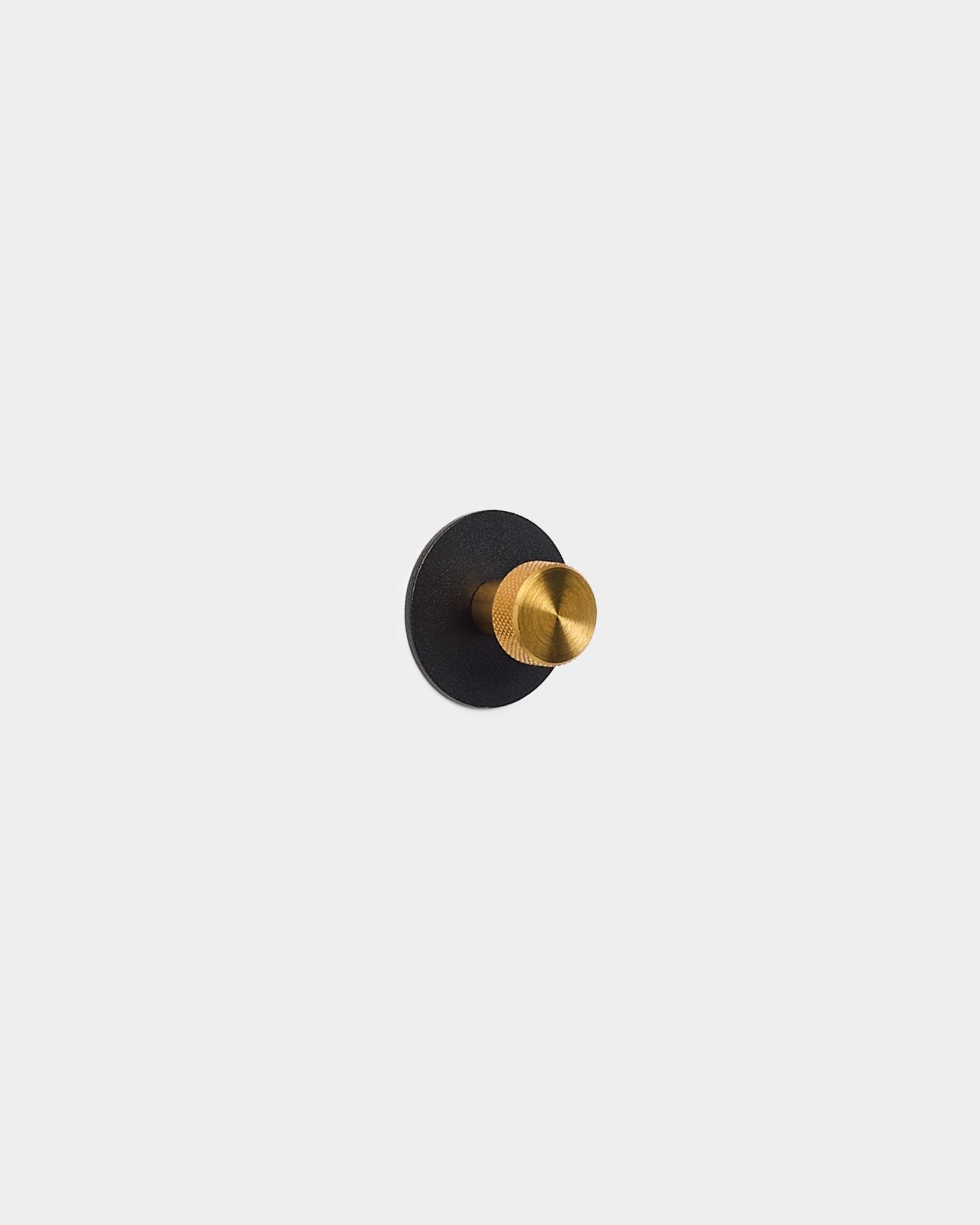 Goudkleurige kapstokhaak op een ronde basis van black Akupanel Akoestisch paneel, gemaakt van gepoedercoat steel door WoodUpp.