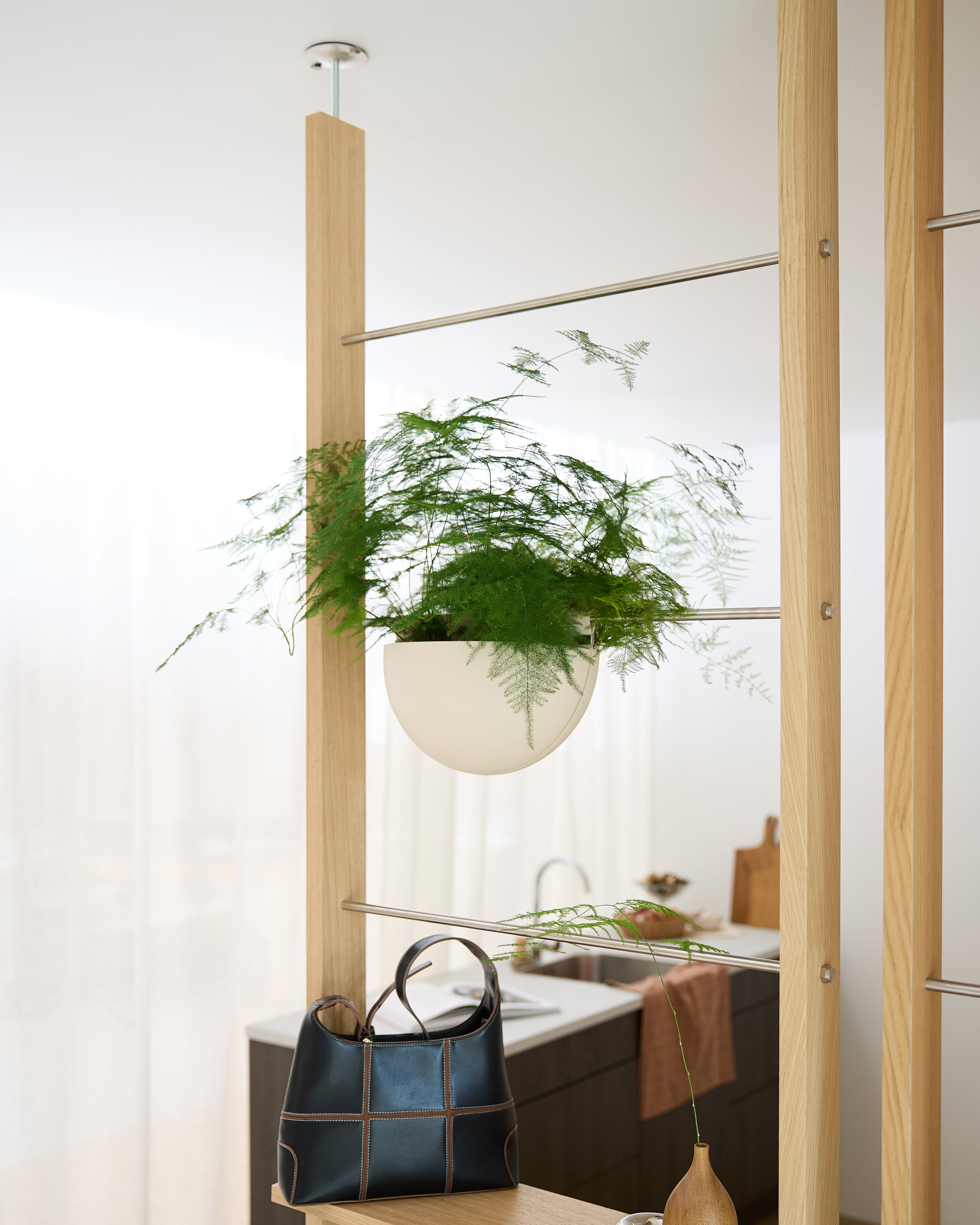 Een Gro Soft Pocket (4L) van WoodUpp is op een houten frame boven een zwarte handtas bevestigd in een lichte, moderne keuken.