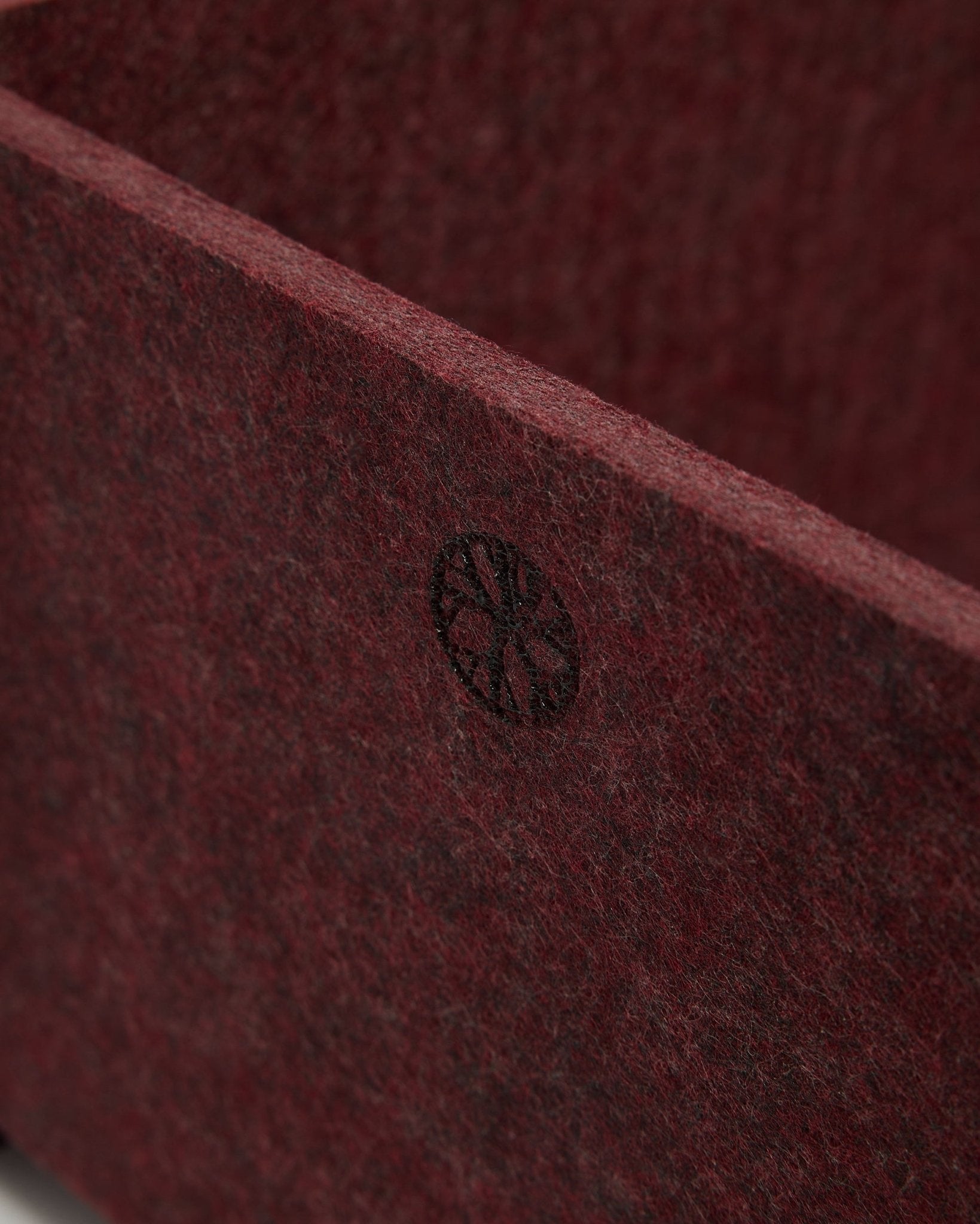Close-up van WoodUpp Vigg | Felt Box / BM2 in ox red, met zichtbaar PET-vilt met textuur en een rond black-embleem in de hoek. Scandinavisch design voor akoestische accessoires.