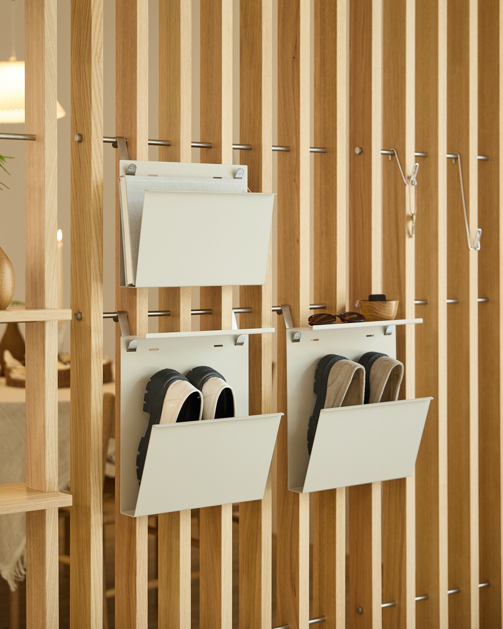 De Nell Magazine Storage van WoodUpp in beige is bevestigd aan een vertical room divider en biedt geordende opbergruimte voor tijdschriften en small spullen.