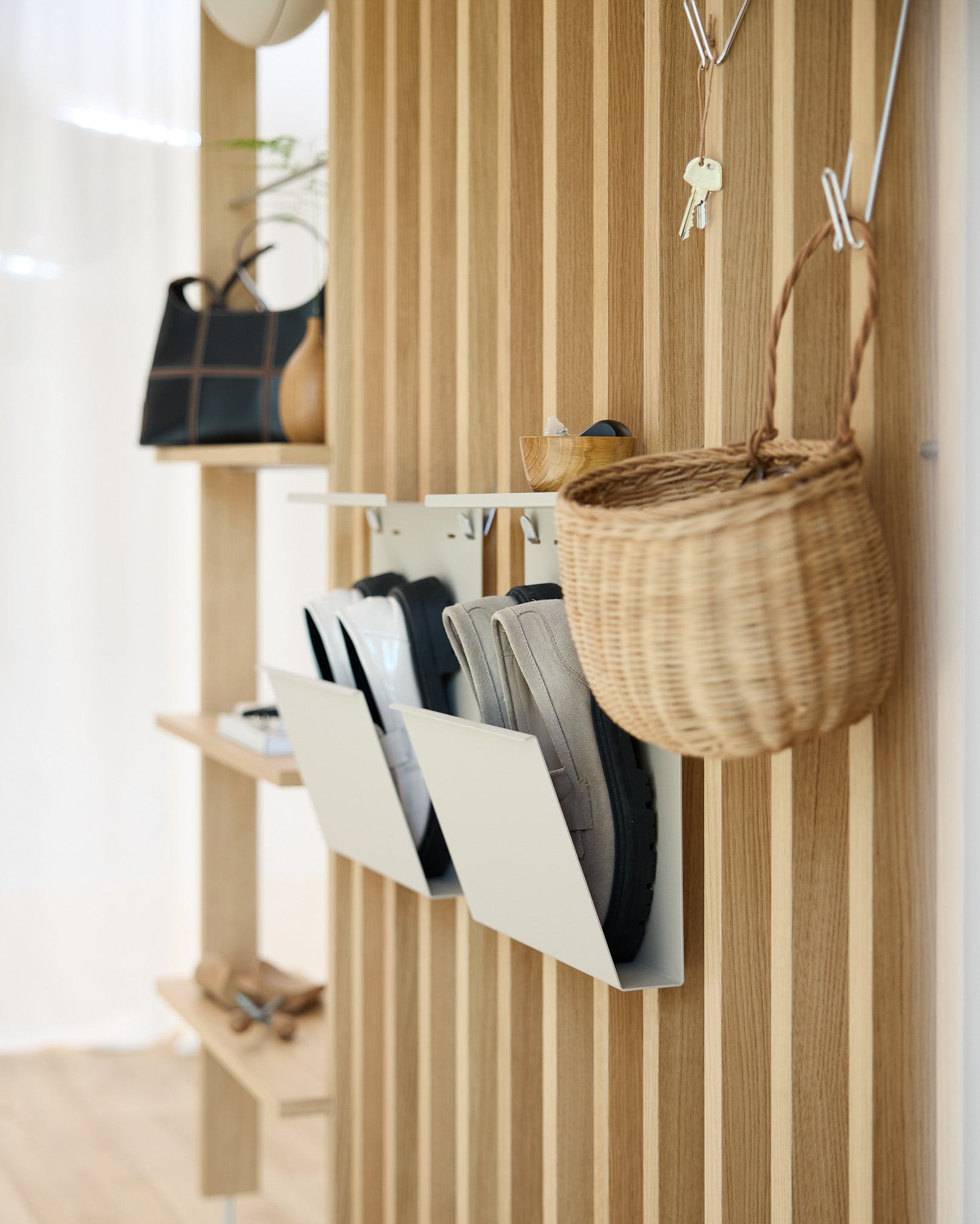 Moderne hal met WoodUpp’s beige Nell Schoenenopberger, Akupanel akoestische houten paneelwanden, wandhaken, een hangmand en een plank met decoratieve items.