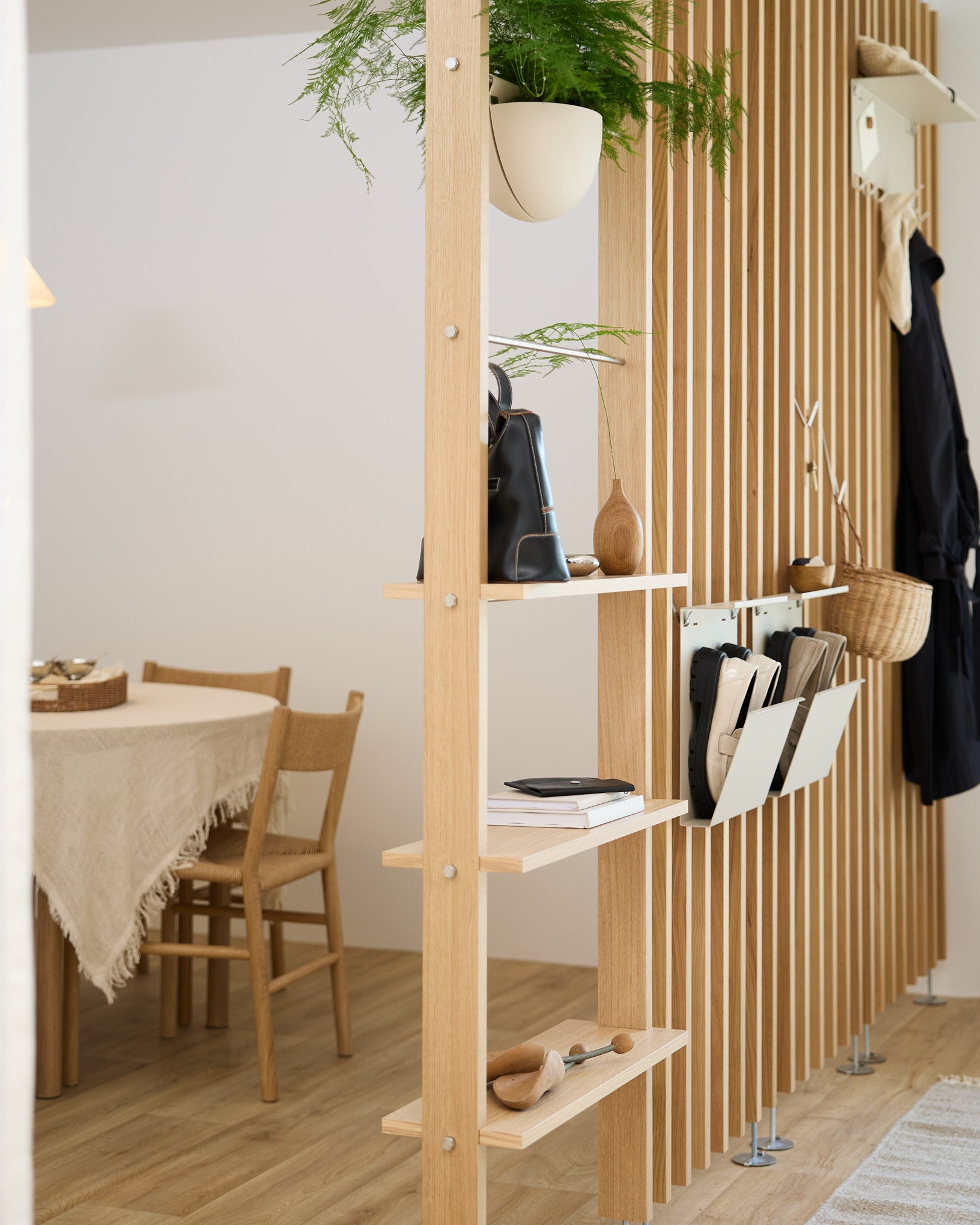 Des étagères ouvertes en bois délimitent l’espace repas, avec le rangement à chaussures Nell en beige de WoodUpp pour un espace de rangement organisé des chaussures dans une maison nordique moderne.