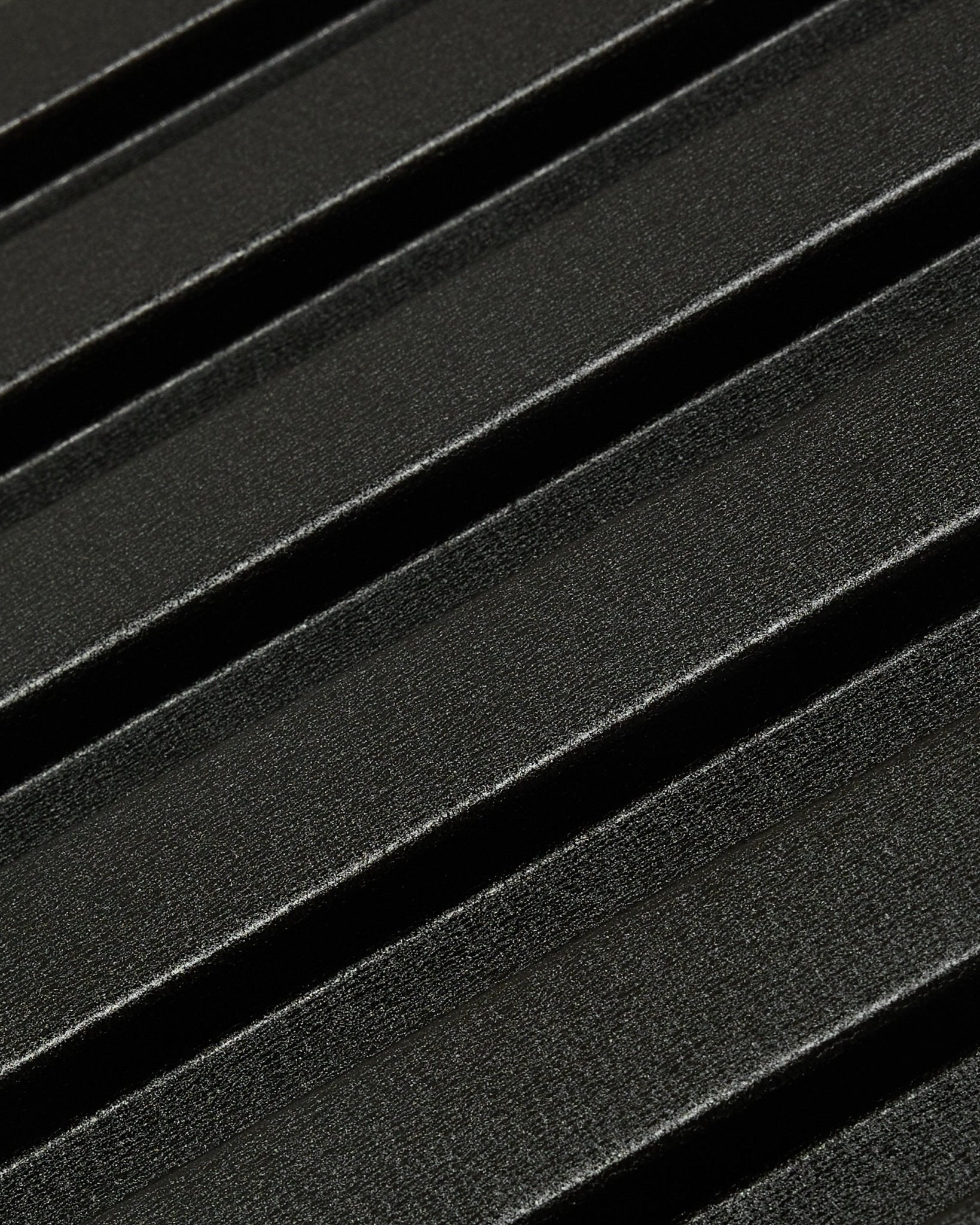 Gros plan sur le panneau de façade extérieur Aluwood de WoodUpp : surface sombre en aluminium recyclé texturé avec des nervures diagonales en relief, dimensions 240 x 45,1 cm.