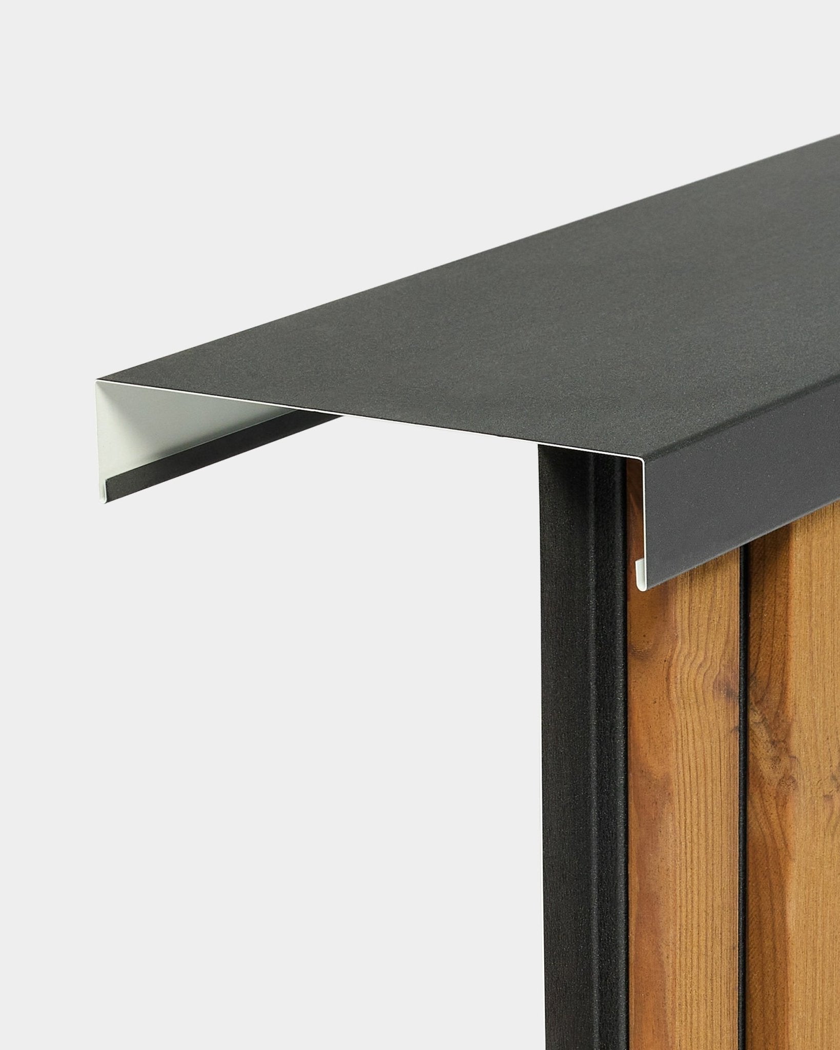 Close-up van de WoodUpp Aluwood Level muurafdekkap (240 cm x 25 cm), gemonteerd op vertical gevelpanelen, waarbij het randdetail tegen een effen achtergrond wordt uitgelicht.