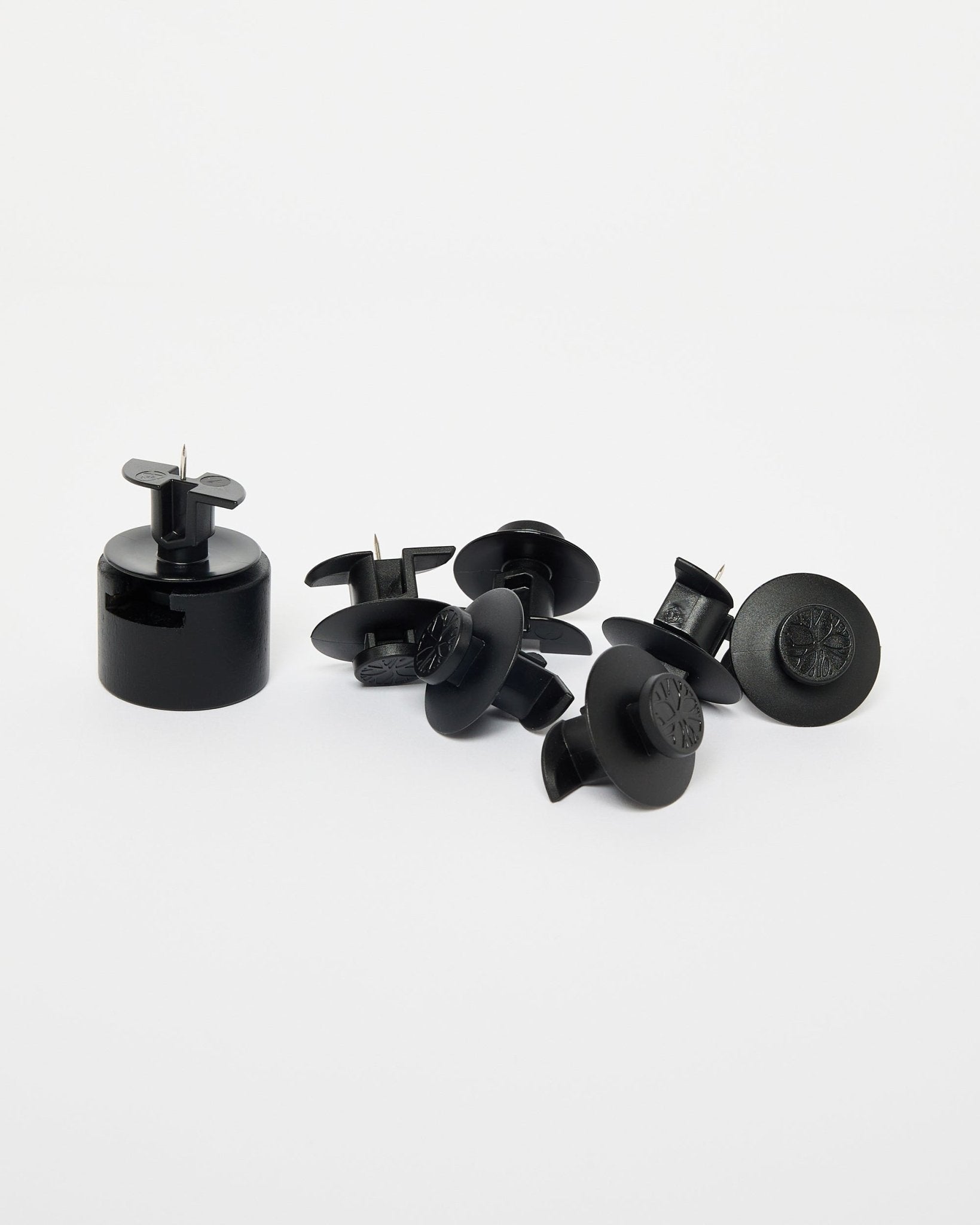 Dupps de WoodUpp : sept attaches de sécurité en plastique black, un outil d’installation et des supports en nylon disposés sur un fond blanc uni.