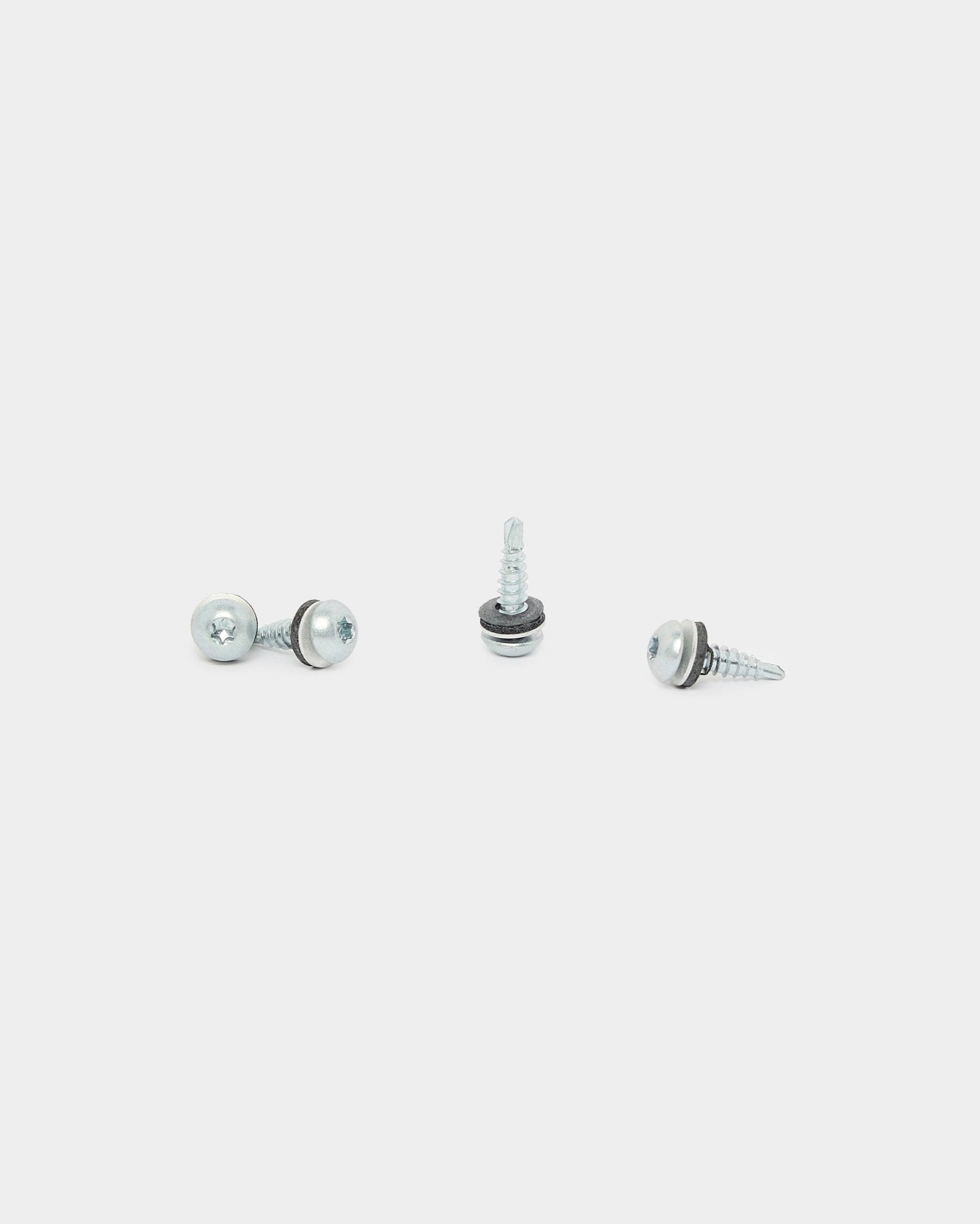 Trois vis WoodUpp Backside black (4.8x19, rondelle Ø10, TX20), utilisées pour l’installation de Panneau acoustique, sont disposées dans différentes directions sur un fond blanc.