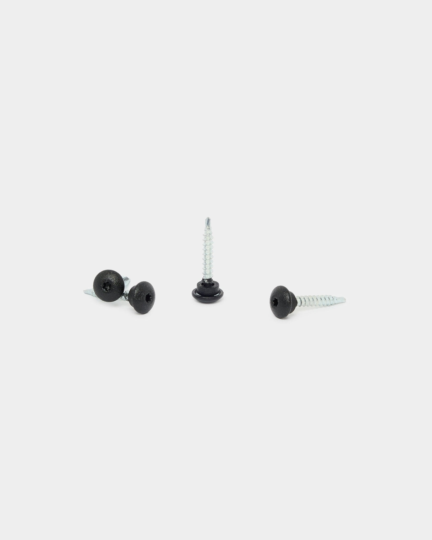 Drie WoodUpp black frontschroeven 4.8x35 met Ø9.5 ringen, ontworpen voor Akupanel akoestische panelen, op een witte achtergrond: één rechtop, twee liggend.