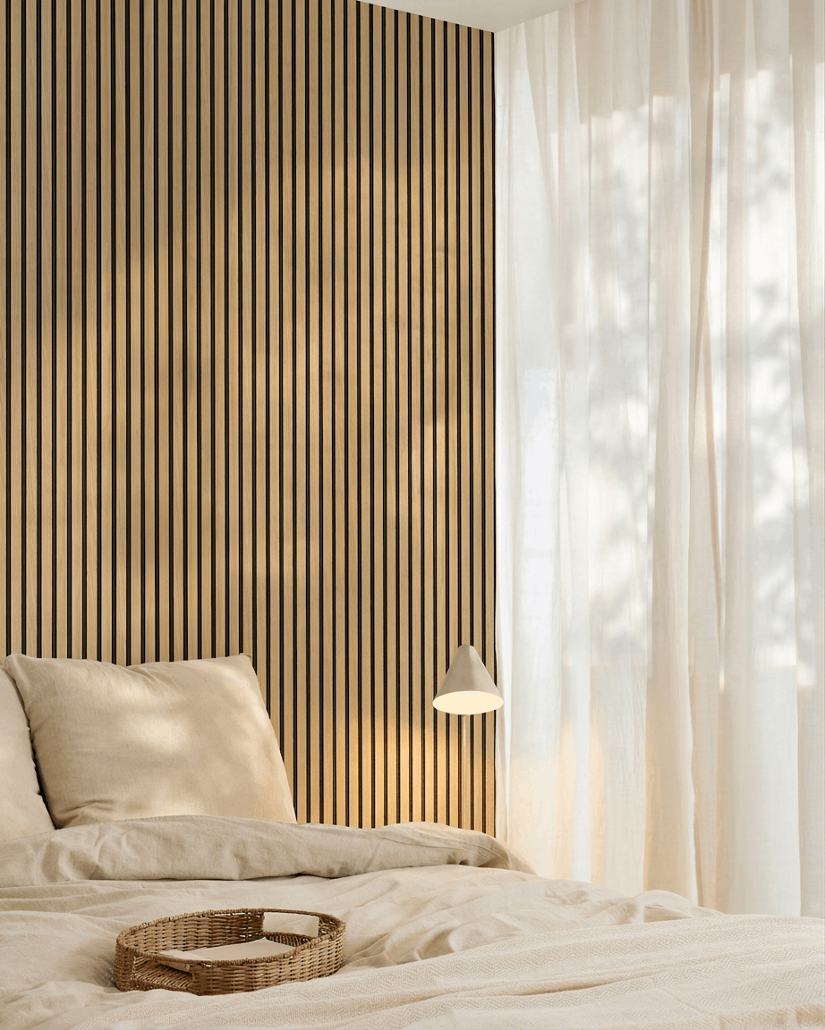 Minimalistische slaapkamer met beige beddengoed, een WoodUpp Akupanel Southern Oak Akoestisch paneel accentmuur, een geweven dienblad op het bed en transparante gordijnen die natuurlijk licht binnenlaten.