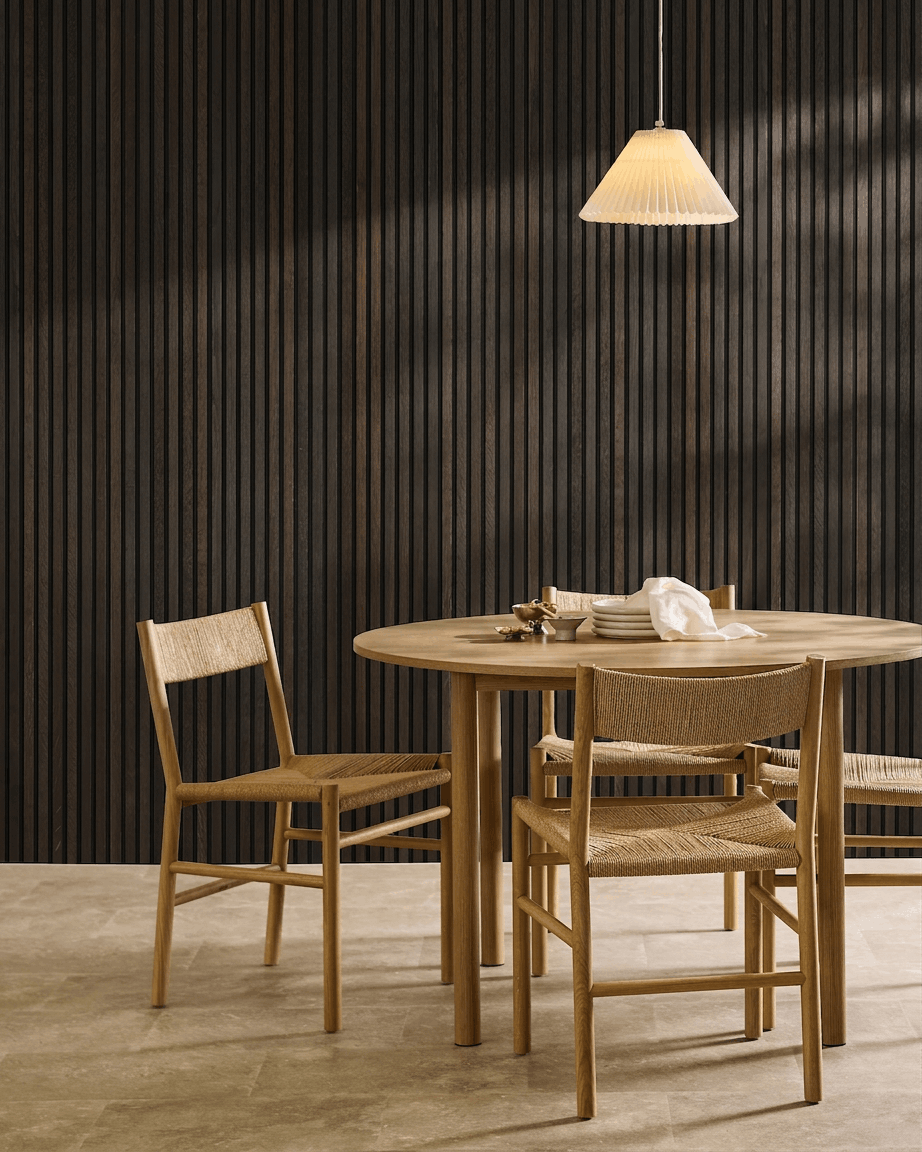Minimalistische eethoek met een houten tafel, Scandinavische stoelen, een hanglamp en een WoodUpp Akupanel Rustic Smoked Oak akoestisch lattenwandpaneel.
