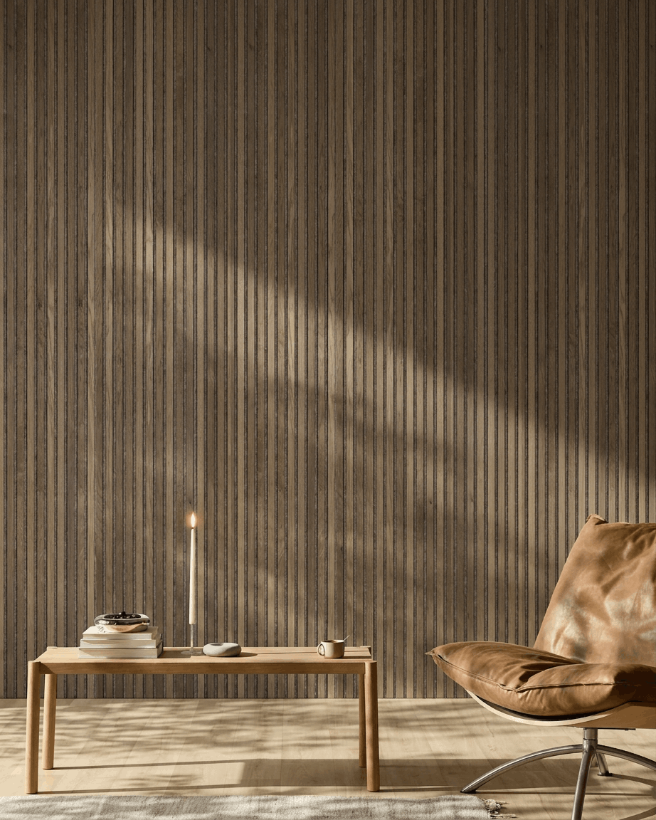 Een moderne ruimte met een brown leren stoel, een houten tafel en een WoodUpp Akupanel in Rustic Grey Oak aan de muur, verlicht door zacht zonlicht.