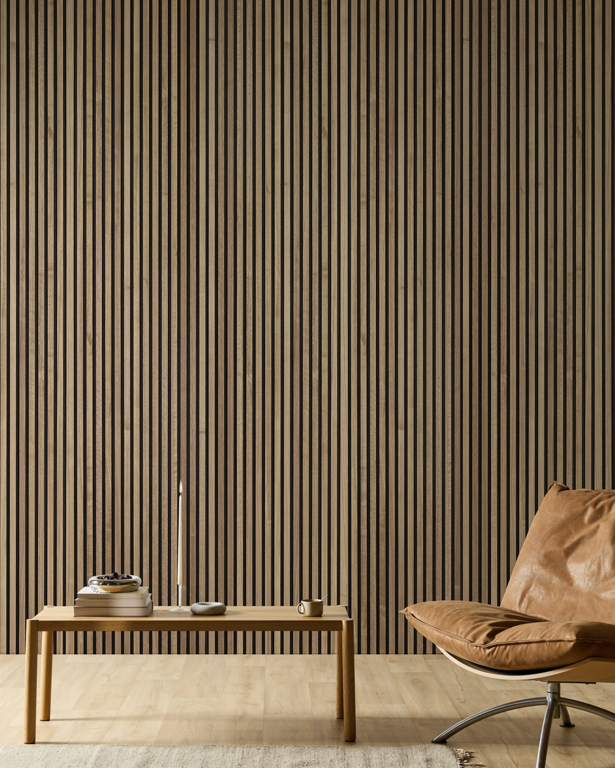 Minimalistische ruimte met een leren stoel, een houten bank, boeken, een kaars en een moderne Akupanel-accentmuur van akoestische houten lamellen in neutrale tinten.