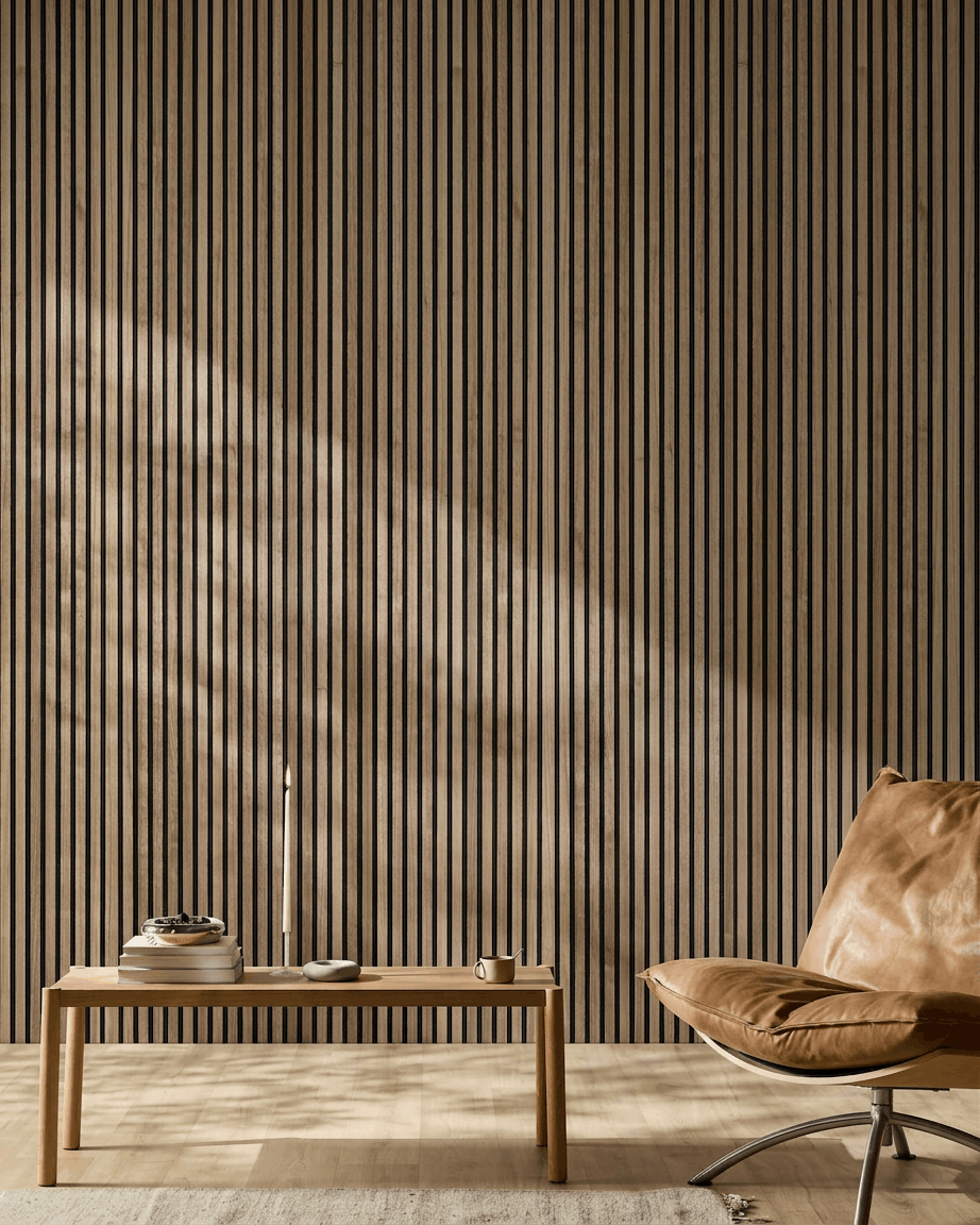 Minimalistische Nordic kamer met een walnut WoodUpp Akupanel akoestisch houten paneel, een stoel van tan leer en een houten salontafel met boeken en een kaars.