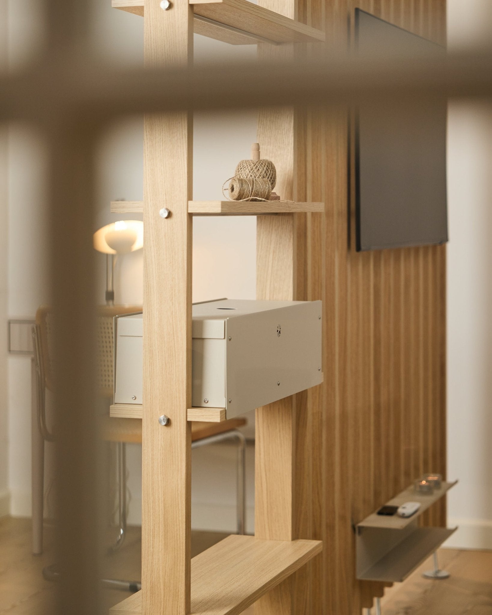 Een sfeervolle kamer met een stoel, lamp en tv toont de Nell | Metal Box / BM2 shelf van WoodUpp, afgewerkt in beige, met minimalistische Nordic decoratie.